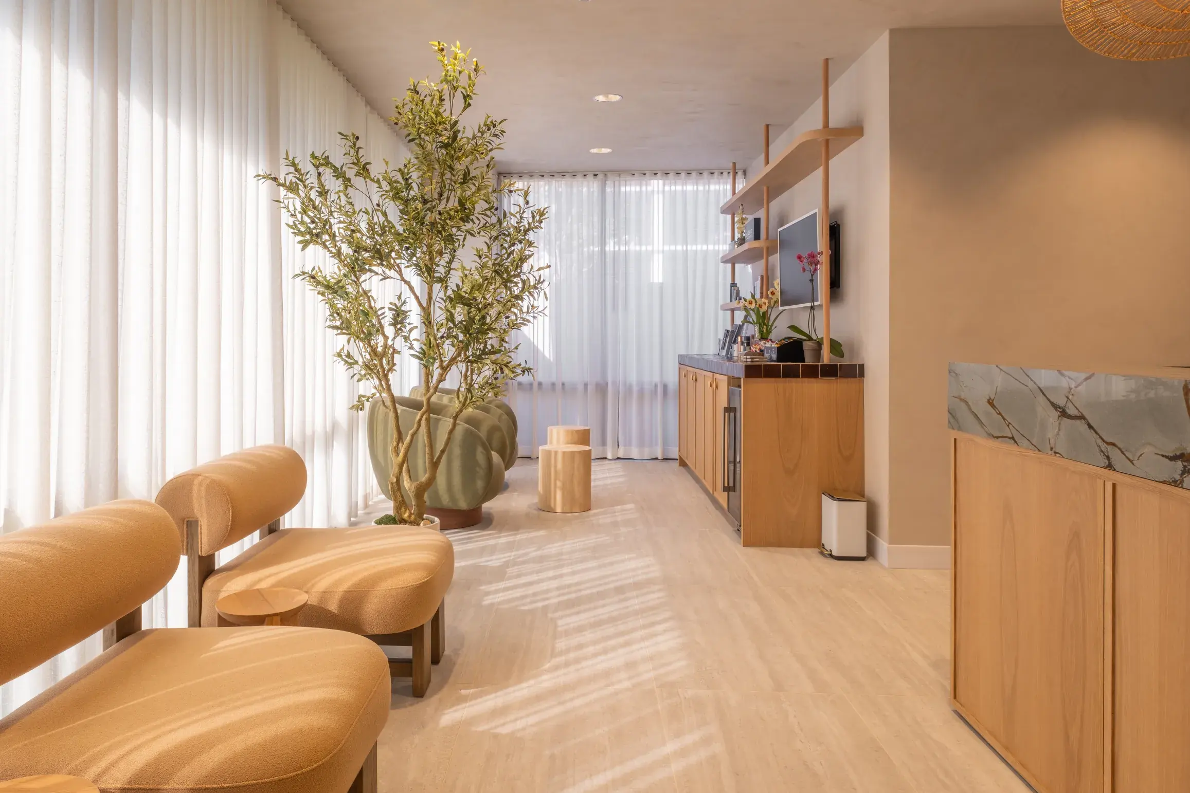 Calista’s reception desk with a marble-patterned surface, pendant light and softly lit shelving.