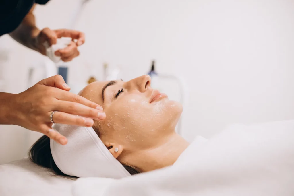 Esthetician applying facial treatment to a relaxed woman in a spa setting